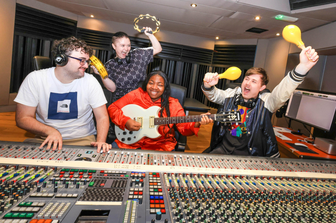 Young musicians at recording studio mixing desk
