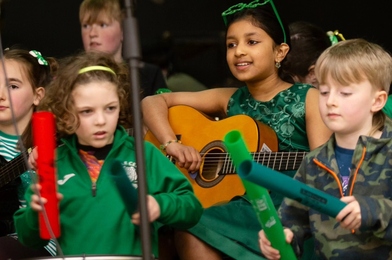 Group of children playing percussion instruments and a guitar.