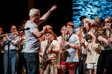 Large group of young wind and brass players performing on stage.