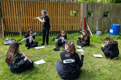 Group of flute players sitting on the grass and practicing.